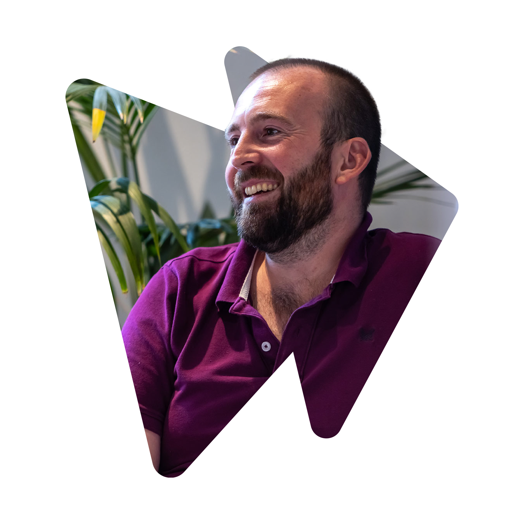 Man in burgundy polo shirt seated in front of a plant