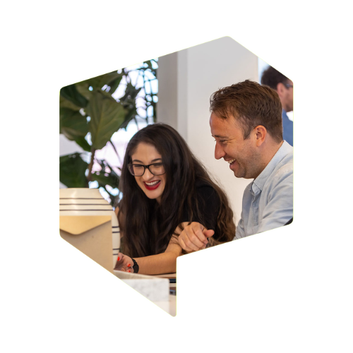 A woman and a man are sat at a table laughing together