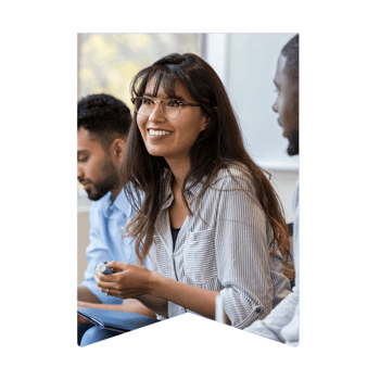 Smiling female employee is attending a briefing meeting, listening to a colleague