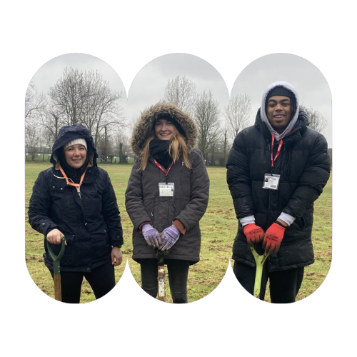 Amy, Jade and Khyron in parka coats with hoods up, standing in a field with spades