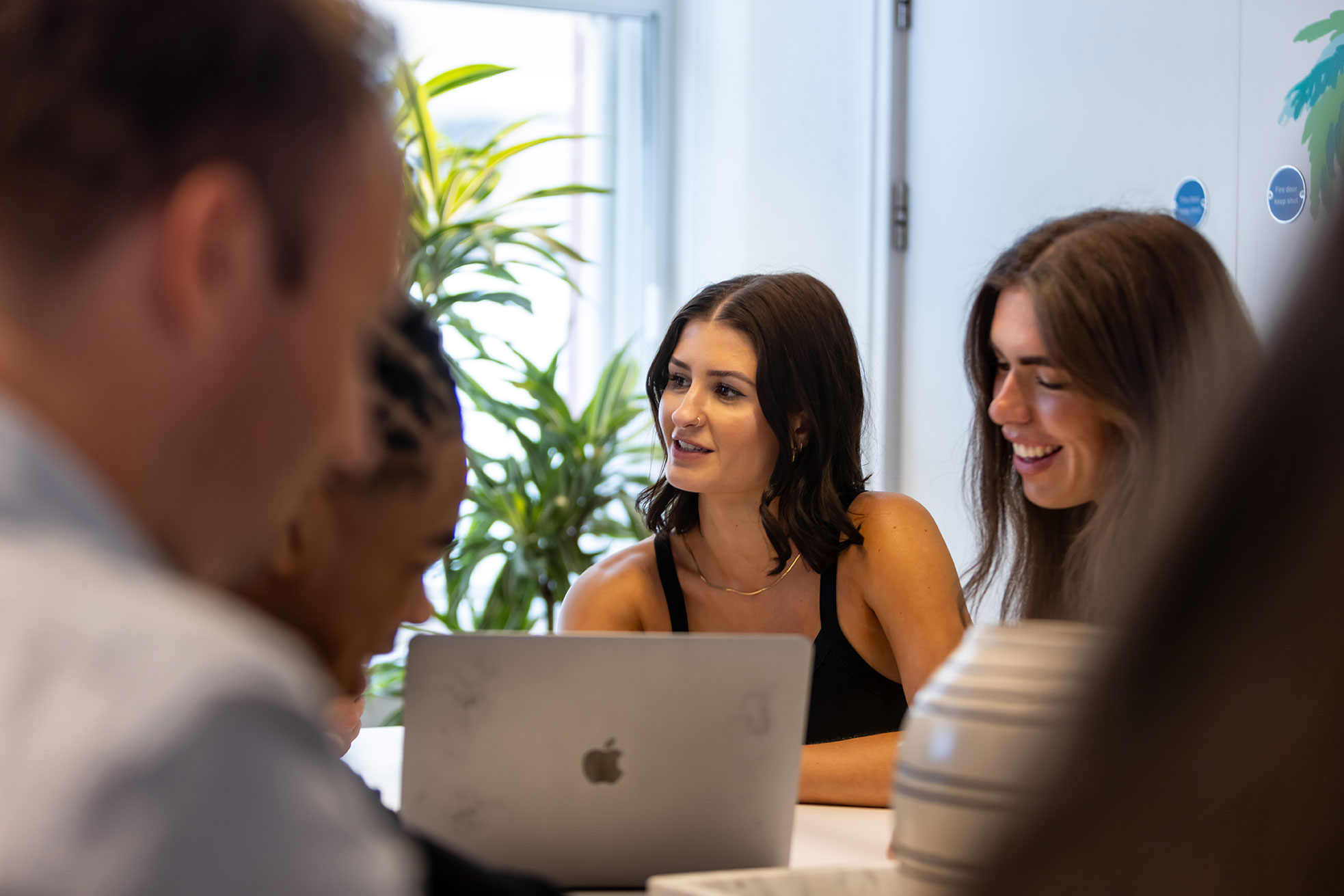 Two women are sat at a table in conversation with an employee who is out of the camera frame